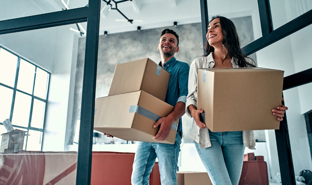 A young married couple in the living room in the house unpack boxes with things